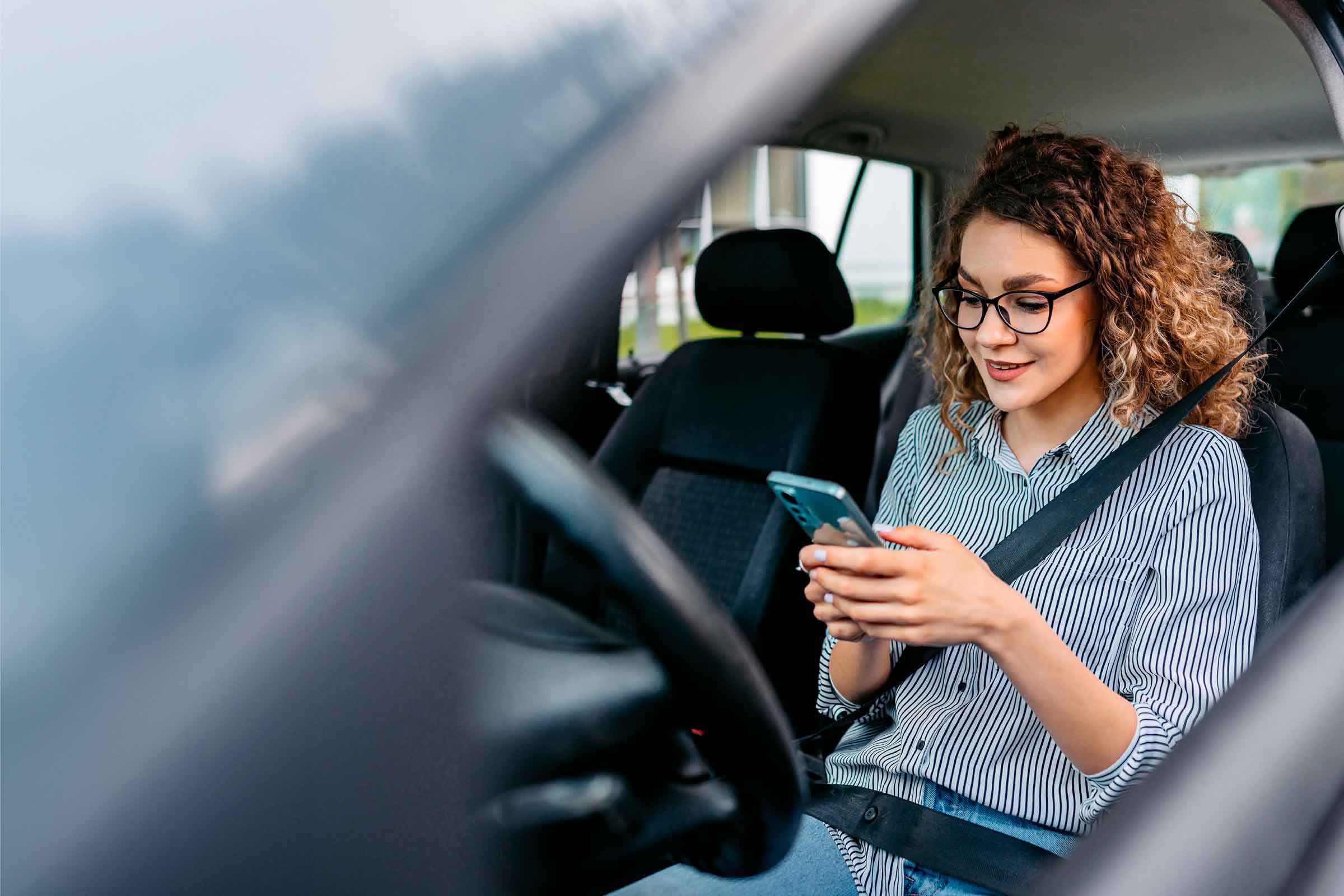 mujer con celular en el carro